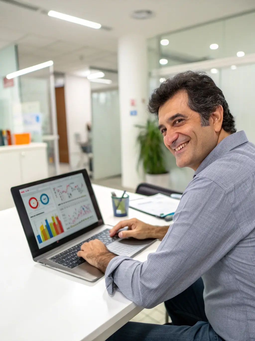 A professional trader smiling confidently while sitting in front of multiple monitors displaying trading charts and financial data, symbolizing the zero upfront cost benefit.
